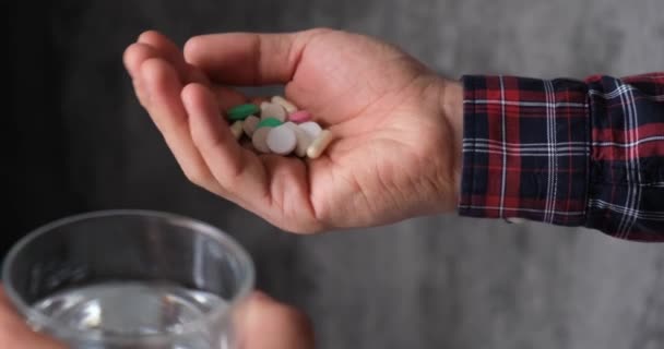 Mann nimmt Medikamente. der Patient nimmt die Tabletten mit einem Glas Wasser, ohne Gesicht — Stockvideo