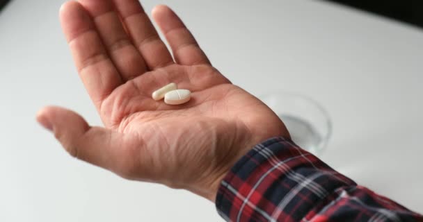 El hombre toma medicamentos. el paciente toma las pastillas con un vaso de agua, sin rostro — Vídeo de stock