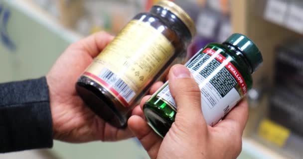 Hombre enfermo leyendo etiqueta en botella de la píldora en la farmacia . — Vídeos de Stock