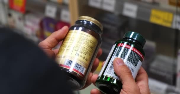 Hombre enfermo leyendo etiqueta en botella de la píldora en la farmacia . — Vídeos de Stock