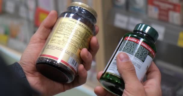 Ziek man lezing label op pil fles bij de apotheek. — Stockvideo