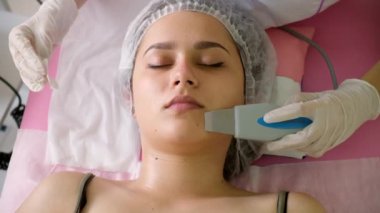 Güzellik uzmanı kadın müşteriler için ultrasonik soyma yapıyor. Kozmetik uzmanı yüz temizleme prosedürü uyguluyor.