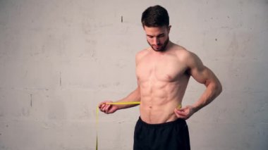 Spor fiziği olan genç bir adam belini ölçer, ne kadar kilo verdiğini kontrol eder. Kilo kaybı, erkekler...