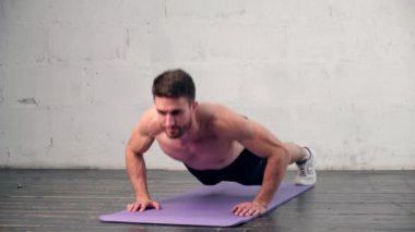 Atletik yapılı genç bir adam evde spor yapmakla meşgul. Şınav. Adam sağlıklı bir hayat sürüyor şınav çeken bir adam.