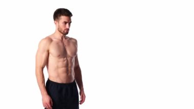 Sakallı, çerçeveye bakıp gülümseyen genç bir sporcu. Erkeklerin çıplak gövdesi ve kaslı kasları. Yakışıklı adam.