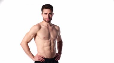 Sakallı, çerçeveye bakıp gülümseyen genç bir sporcu. Erkeklerin çıplak gövdesi ve kaslı kasları. Yakışıklı adam.