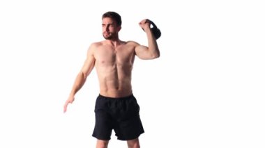 Sakallı, atletik yapılı genç adam beyaz bir arka planda fitness yapıyor. Fitness antrenörü ağırlık kaldırır