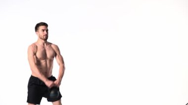 Sakallı, atletik yapılı genç adam beyaz bir arka planda fitness yapıyor. Fitness antrenörü ağırlık kaldırır
