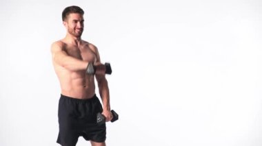 Beyaz arka planda, sakallı, çıplak vücutlu genç yakışıklı adam spor fitness aktivitesi kaldırmakla meşgul.