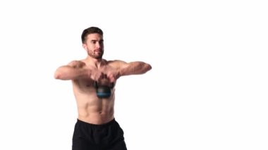 Sakallı, atletik yapılı genç adam beyaz bir arka planda fitness yapıyor. Fitness antrenörü ağırlık kaldırır