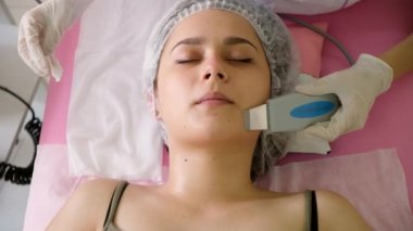 Güzellik uzmanı kadın müşteriler için ultrasonik soyma yapıyor. Kozmetik uzmanı yüz temizleme prosedürü uyguluyor.