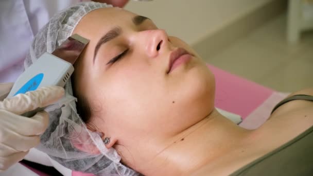 Beauty Specialist Makes Ultrasonic Peeling For Female Clients Face. Cosmetologist doing procedure of cleaning face with — Stock Video