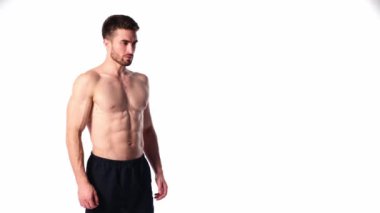 Sakallı, çerçeveye bakıp gülümseyen genç bir sporcu. Erkeklerin çıplak gövdesi ve kaslı kasları. Yakışıklı adam.