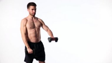 Beyaz arka planda, sakallı, çıplak vücutlu genç yakışıklı adam spor fitness aktivitesi kaldırmakla meşgul.