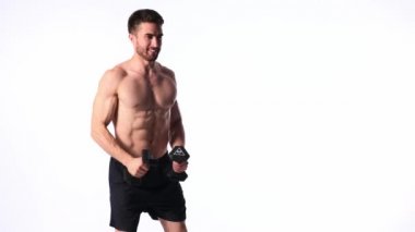 Beyaz arka planda, sakallı, çıplak vücutlu genç yakışıklı adam spor fitness aktivitesi kaldırmakla meşgul.