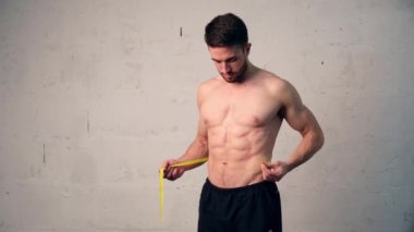 Spor fiziği olan genç bir adam belini ölçer, ne kadar kilo verdiğini kontrol eder. Kilo kaybı, erkekler...