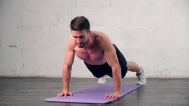 Atletik yapılı genç bir adam evde spor yapmakla meşgul. Şınav. Adam sağlıklı bir hayat sürüyor şınav çeken bir adam.