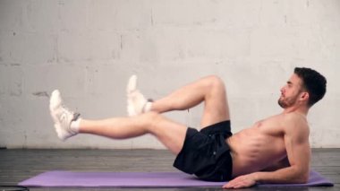 Genç bir sporcu karın kasları için egzersiz yapıyor. Sakallı adam evde spor yapıyor.