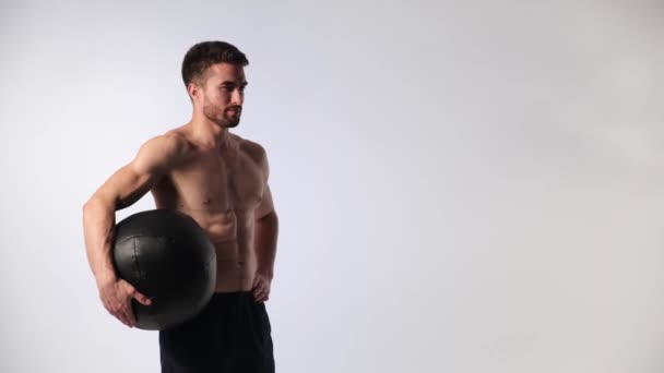 Bebaarde knappe sportman met een medball in zijn handen op een witte achtergrond — Stockvideo