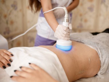 Donanım kozmetolojisi. Vücut bakımı. Spa tedavisi. Ultrason boşluğu, vücut hatları, tedavi. Kadın güzellik salonunda anti-selülit ve anti-yağ tedavisi görüyor..