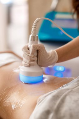 Donanım kozmetolojisi. Vücut bakımı. Spa tedavisi. Ultrason boşluğu, vücut hatları, tedavi. Kadın güzellik salonunda anti-selülit ve anti-yağ tedavisi görüyor..