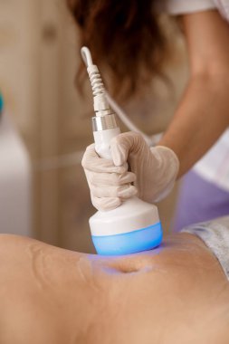 Donanım kozmetolojisi. Vücut bakımı. Spa tedavisi. Ultrason boşluğu, vücut hatları, tedavi. Kadın güzellik salonunda anti-selülit ve anti-yağ tedavisi görüyor..