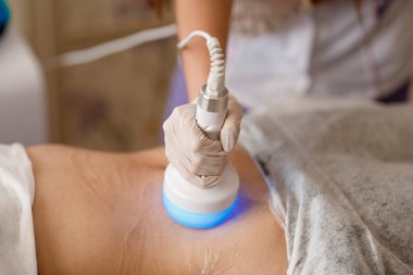 Donanım kozmetolojisi. Vücut bakımı. Spa tedavisi. Ultrason boşluğu, vücut hatları, tedavi. Kadın güzellik salonunda anti-selülit ve anti-yağ tedavisi görüyor..