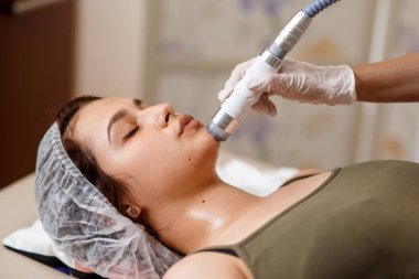 Lenfatik drenaj masajı LPG aygıtı işlemi. Terapist güzellik uzmanı spa salonundaki kadın için canlandırıcı bir yüz masajı yapıyor. Güzellik ve vücut bakımı kavramı.