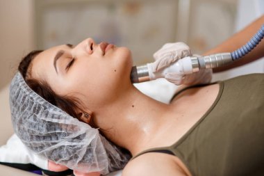 Lenfatik drenaj masajı LPG aygıtı işlemi. Terapist güzellik uzmanı spa salonundaki kadın için canlandırıcı bir yüz masajı yapıyor. Güzellik ve vücut bakımı kavramı.