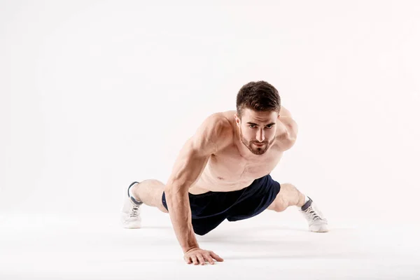 Joven con barba de una física deportiva que hace subir desde el suelo sobre un fondo blanco aislado, el deportista entra en el deporte. — Foto de Stock