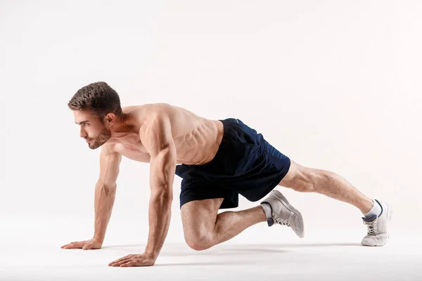 Ung man med skägg av en sport fysik gör en övning på musklerna i bukhålan på en vit isolerad bakgrund, idrottaren går in för sport, motion på musklerna i pressen — Stockfoto