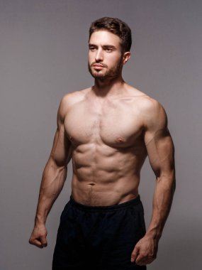 Beyaz arka planda atletik bir adam. Yakışıklı sakallı sporcu dört gözle bekliyor..