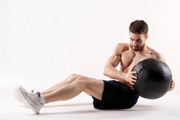 Ung man med skägg av en sport fysik gör en övning på musklerna i bukhålan på en vit isolerad bakgrund, idrottaren går in för sport, motion på musklerna i pressen — Stockfoto