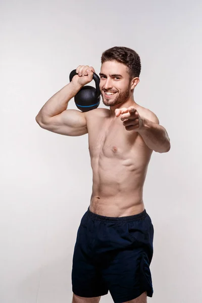 Atleta jovem em um fundo branco levanta um kettlebell. treinamento de um homem barbudo atlético construir — Fotografia de Stock