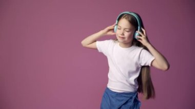 Küçük kız kulaklıkla müzik dinliyor, bir çocuk pembe arka planda dans ediyor.