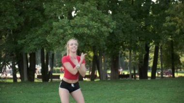 Genç bir kız spor için doğaya gider. Egzersiz ve açık havada esneme. Parkta koşuya hazırlık. Sarışın