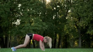 Genç bir kadın doğada yoga yapıyor. Açık havada dur..