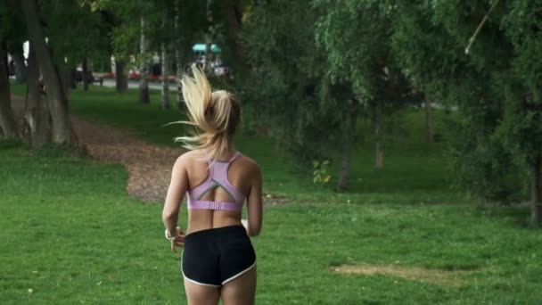 Een jong meisje gaat sporten in de natuur. joggen buiten, cardiotraining in het park — Stockvideo