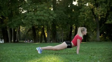 Genç bir kadın doğada yoga yapıyor. Açık havada esneme egzersizleri. Parktaki spor salonunda.