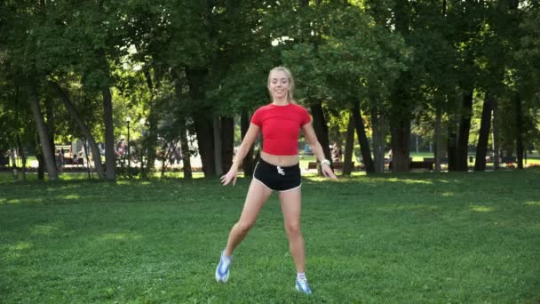 Chica joven se está entrenando en la naturaleza. entrenamiento cardiovascular en su lugar. Aptitud intensa en el parque. rubia entra para los deportes — Vídeo de stock
