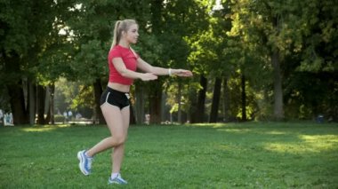 Genç bir kadın doğada yoga yapıyor. Açık havada esneme egzersizleri. Parktaki spor salonunda.