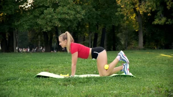 Junges Mädchen ist in Fitness an der frischen Luft engagiert, eine Frau treibt Sport im Park, bewegt sich auf der Beerenallee — Stockvideo