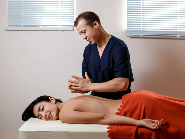 Una joven recibe un procedimiento de masaje. Masajista hace masaje de espalda. — Foto de Stock