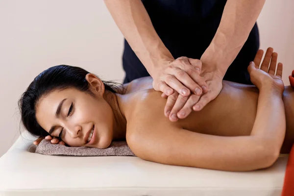 Een jonge vrouw krijgt een massage. Masseur maakt terug massage. — Stockfoto