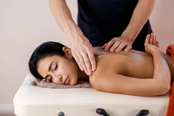 Eine junge Frau bekommt einen Massagevorgang. Masseur Marken Rücken Massage. — Stockfoto