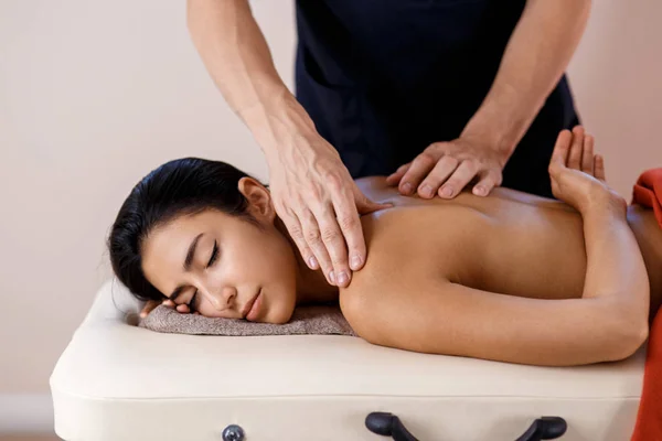 A young woman gets a massage procedure. Masseur makes back massage. — Stock Photo, Image