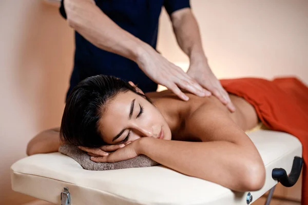 Een jonge vrouw krijgt een massage. Masseur maakt terug massage. — Stockfoto