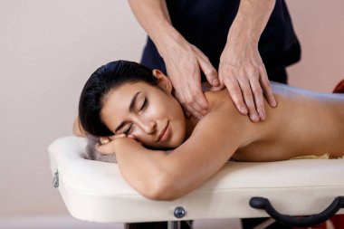 Genç bir kadın masaj prosedürü yaptırıyor. Masör Sırt Masajı Yapıyor.