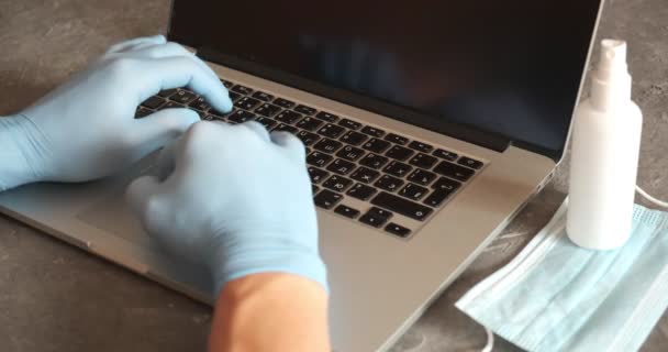 Junger indischer Geschäftsmann trägt Handschuhe mit medizinischer Gesichtsmaske und arbeitet am Laptop am heimischen Schreibtisch — Stockvideo