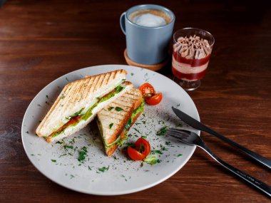 Kızarmış tavuk göğsü ve salata sandviçi. Kahverengi bir kağıda sarılmış, ahşap bir masada servis ediliyor.